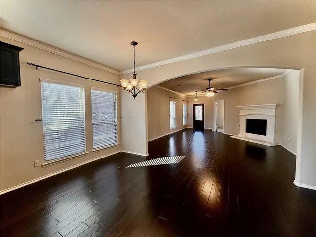 a view of a livingroom with wooden floor a ceiling fan and a kitchen