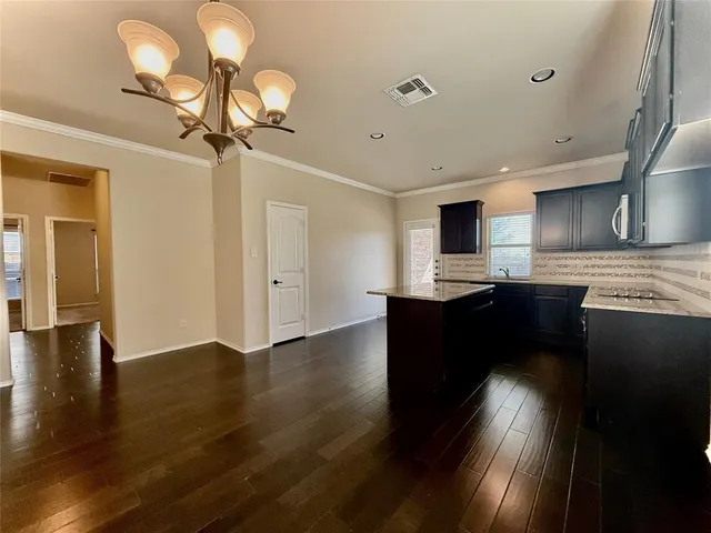a kitchen with granite countertop a stove cabinets and wooden floor