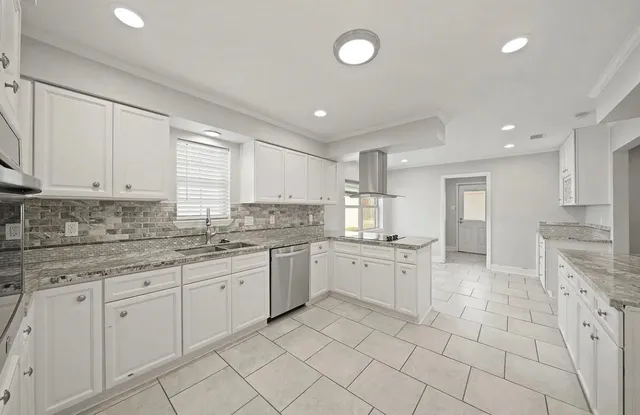 a large kitchen with granite countertop white cabinets white appliances with a sink and dishwasher