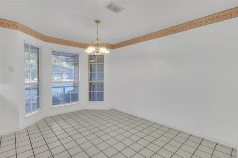 a view of an empty room with window and chandelier fan