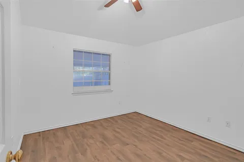 an empty room with wooden floor & windows