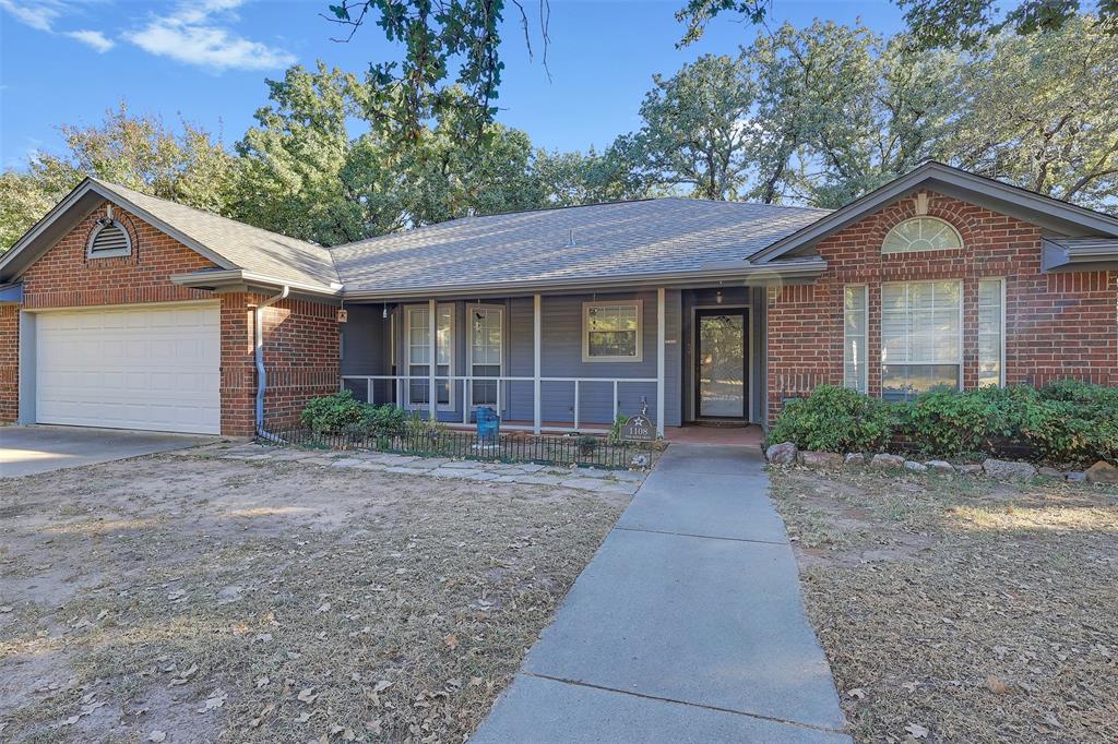 1108 Pine Ridge Drive Azle, TX 76020 - Photo 5 of 40 a view of a brick house with a yard plants and large tree