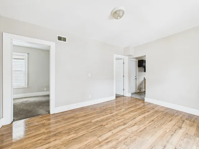 a view of a livingroom with wooden floor and a hallway