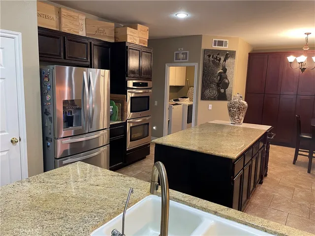 a kitchen with stainless steel appliances kitchen island granite countertop a refrigerator a stove and a sink with wooden floor