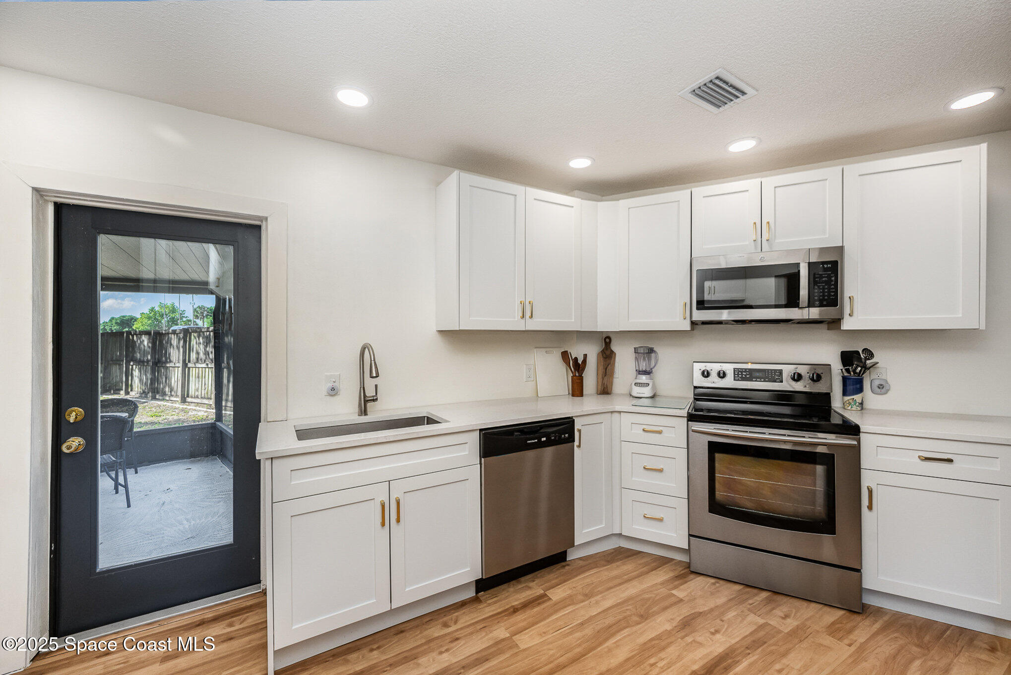 233 Beverly Road Cocoa, FL 32922 - Photo 8 of 20 a kitchen with stainless steel appliances granite countertop a stove top oven a sink and white cabinets with wooden floor