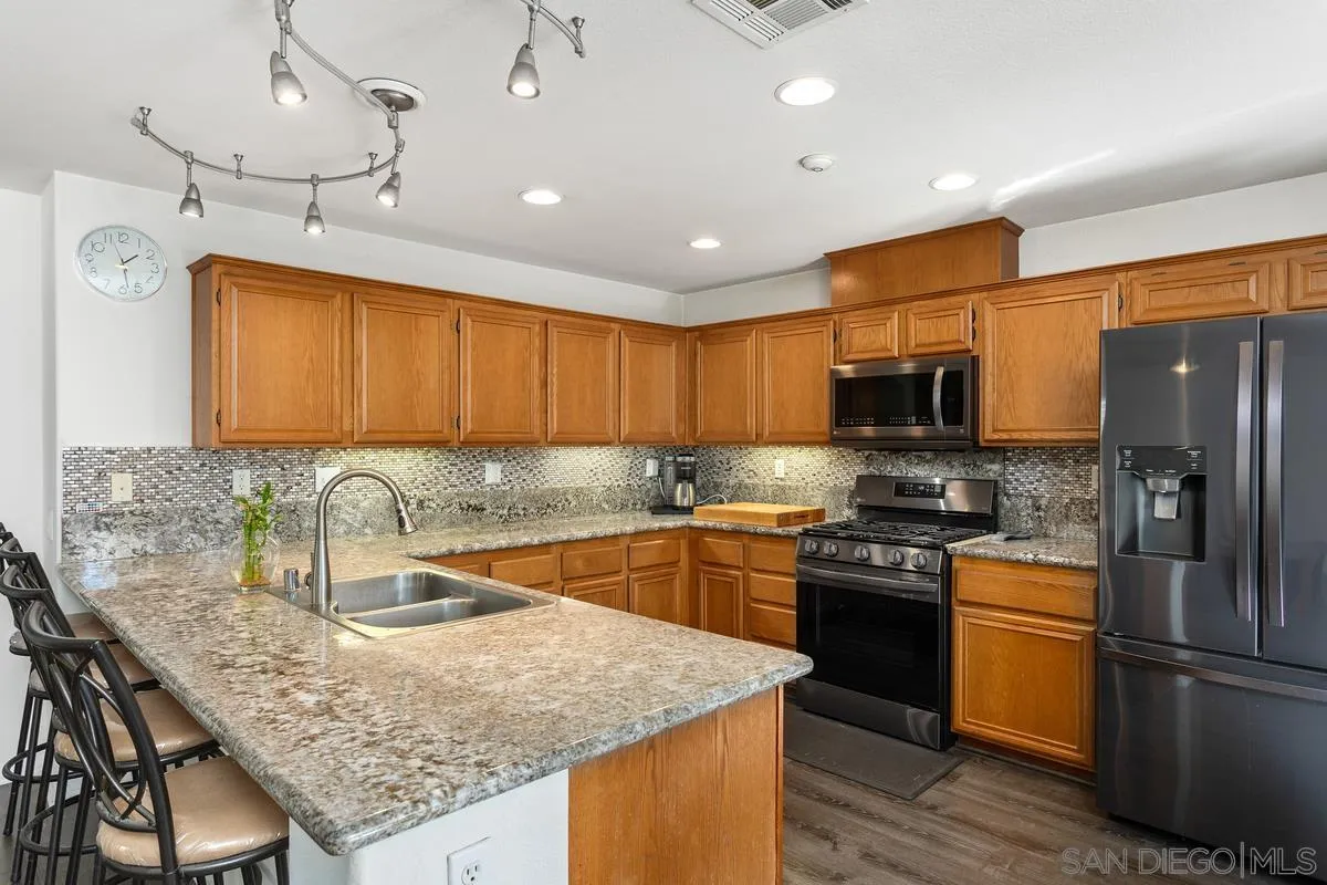 5145 Mendip Street Oceanside, CA 92057 - Photo 11 of 33 a kitchen with stainless steel appliances granite countertop a sink stove refrigerator and cabinets