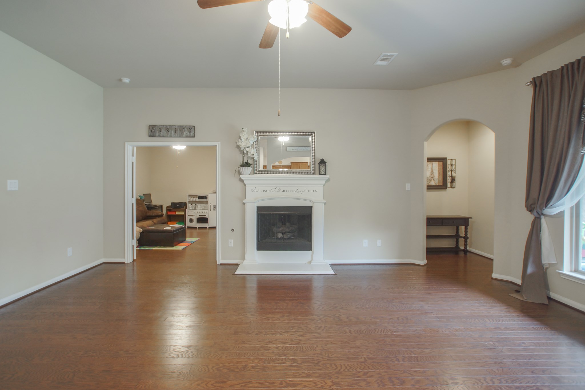 111 Pheasant Run Drive Conroe, TX 77384 - Photo 13 of 50 an empty room with a fireplace and chandelier fan