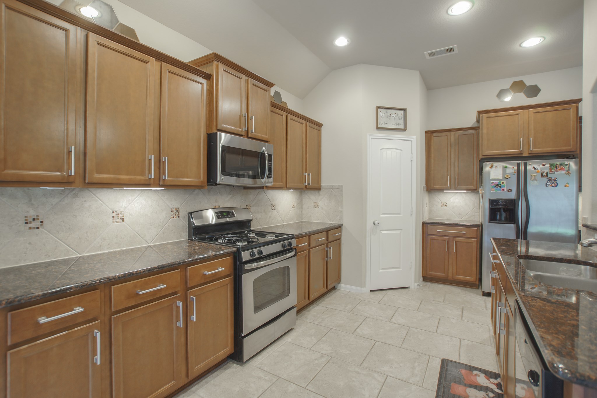 111 Pheasant Run Drive Conroe, TX 77384 - Photo 21 of 50 a kitchen with stainless steel appliances granite countertop a stove a sink and a microwave