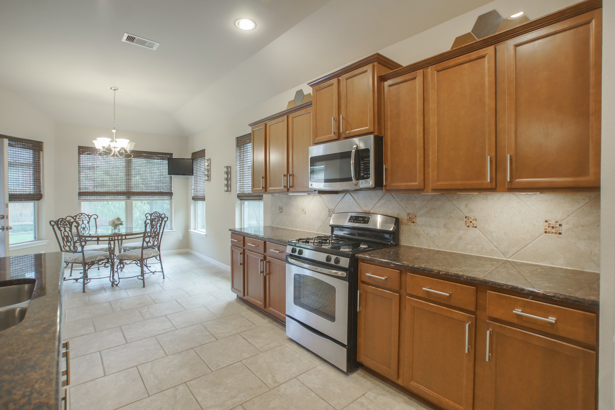 111 Pheasant Run Drive Conroe, TX 77384 - Photo 22 of 50 a kitchen with stainless steel appliances granite countertop a stove top oven a sink dishwasher a dining table and chairs with wooden floor