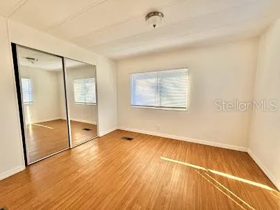 an empty room with wooden floor and a ceiling fan