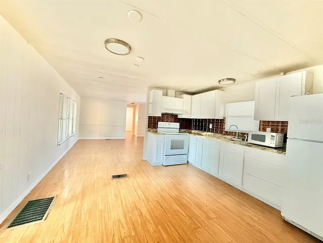 a large kitchen with cabinets and wooden floor