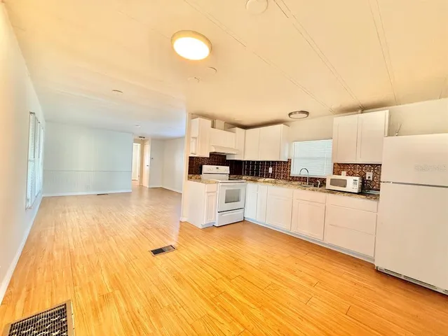 a kitchen with granite countertop a sink cabinets and wooden floor