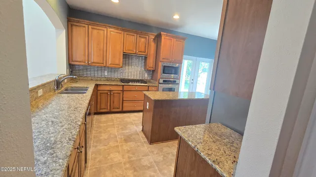 a kitchen with granite countertop a sink stove and cabinets