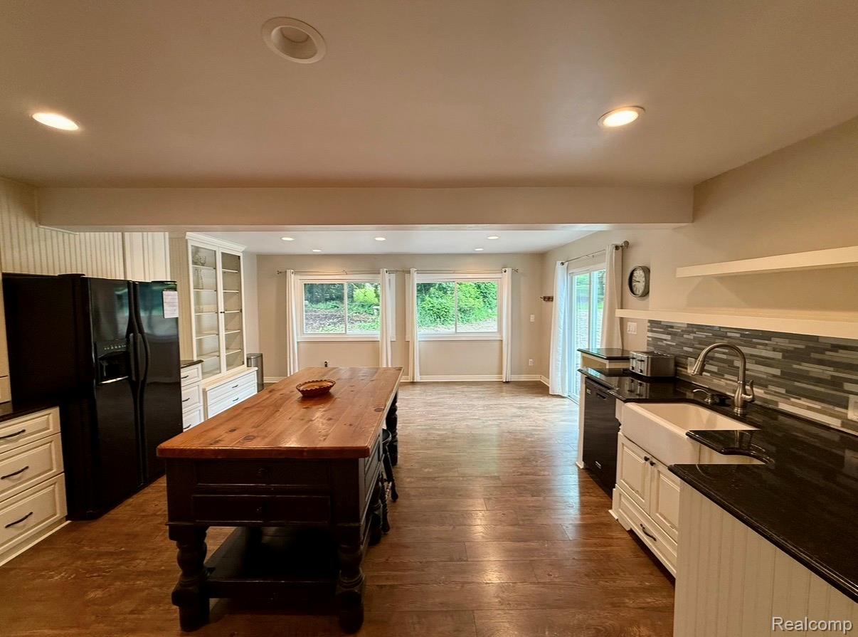 2360 Oklahoma Avenue Rochester, MI 48309 - Photo 14 of 36 Spacious kitchen featuring a large wood-top island, dark wood-finish flooring, white cabinetry with black hardware, black countertops, and an integrated farmhouse sink