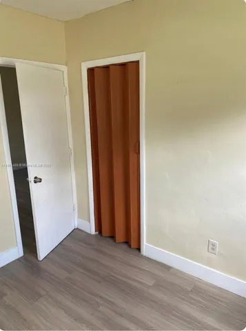 an empty room with wooden floor and closet