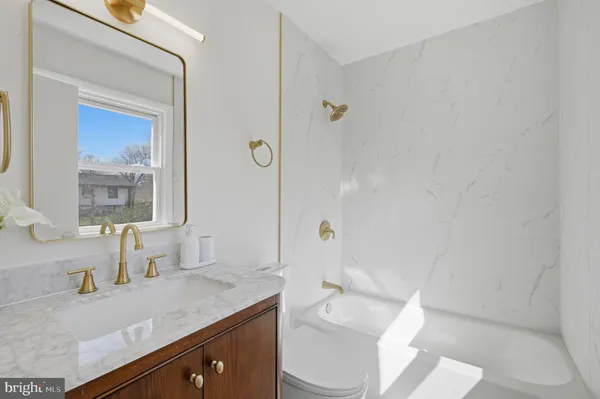 a bathroom with a granite countertop sink a toilet and a mirror