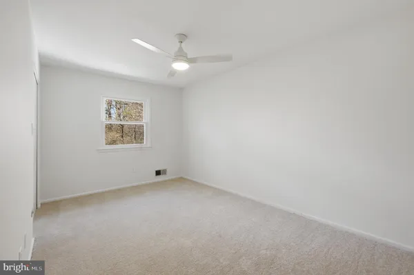 an empty room with a fan & a window