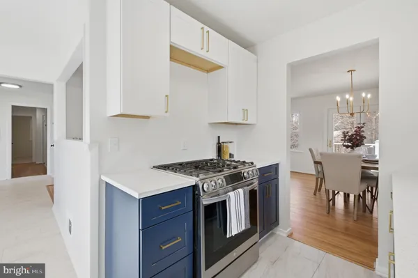 a kitchen with stainless steel appliances a stove a white cabinets and wooden floor