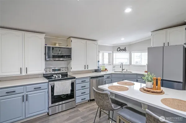 a kitchen with a sink a stove a refrigerator and white cabinets
