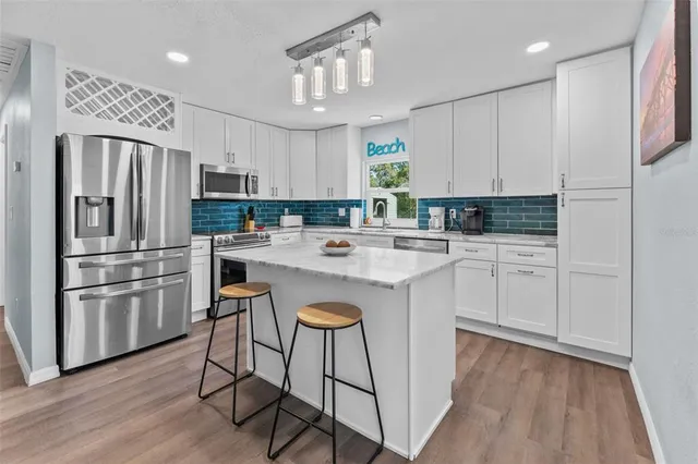 a kitchen with kitchen island granite countertop a sink cabinets and stainless steel appliances