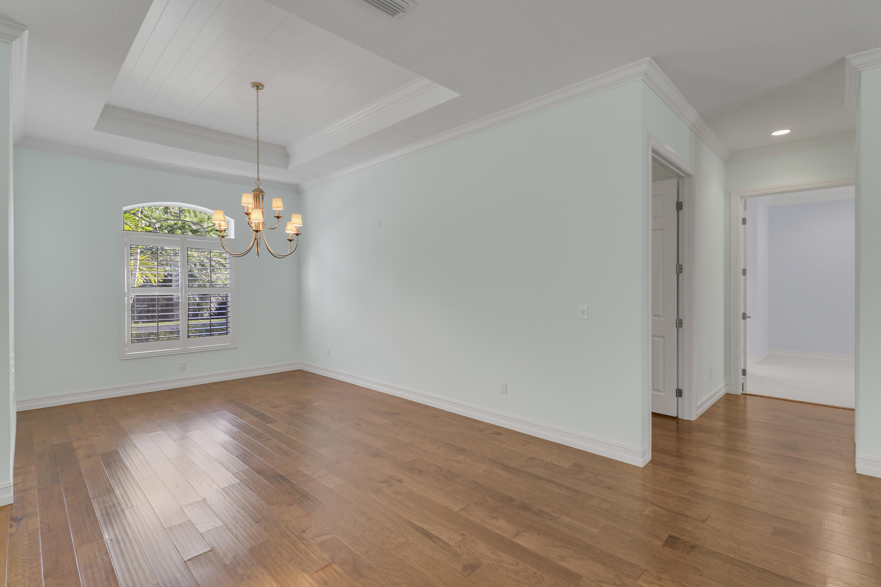 8415 Southeast Governors Way Hobe Sound, FL 33455 - Photo 46 of 105 an empty room with wooden floor chandelier and windows