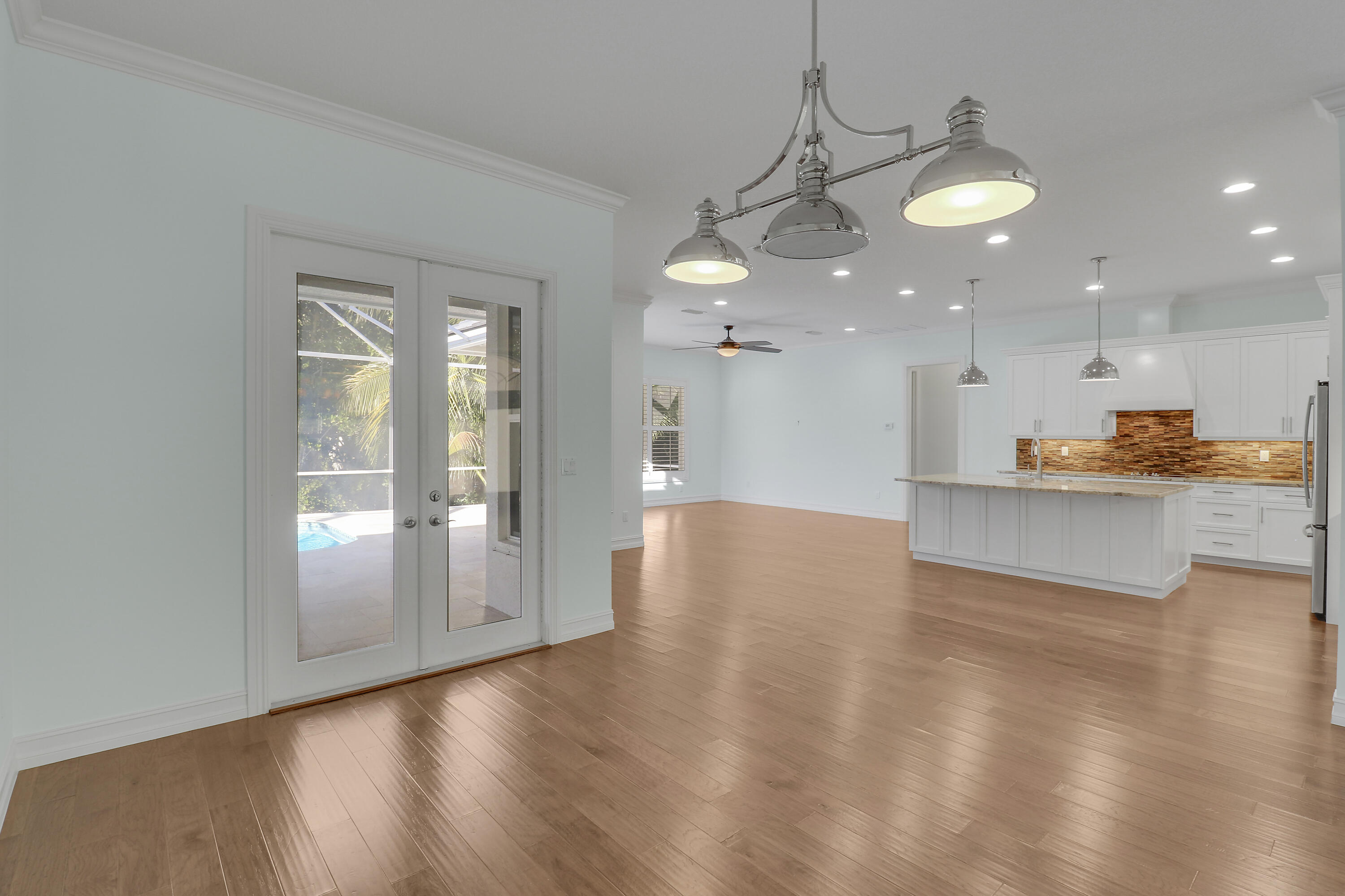 8415 Southeast Governors Way Hobe Sound, FL 33455 - Photo 51 of 105 a view of a kitchen and an empty room with wooden floor
