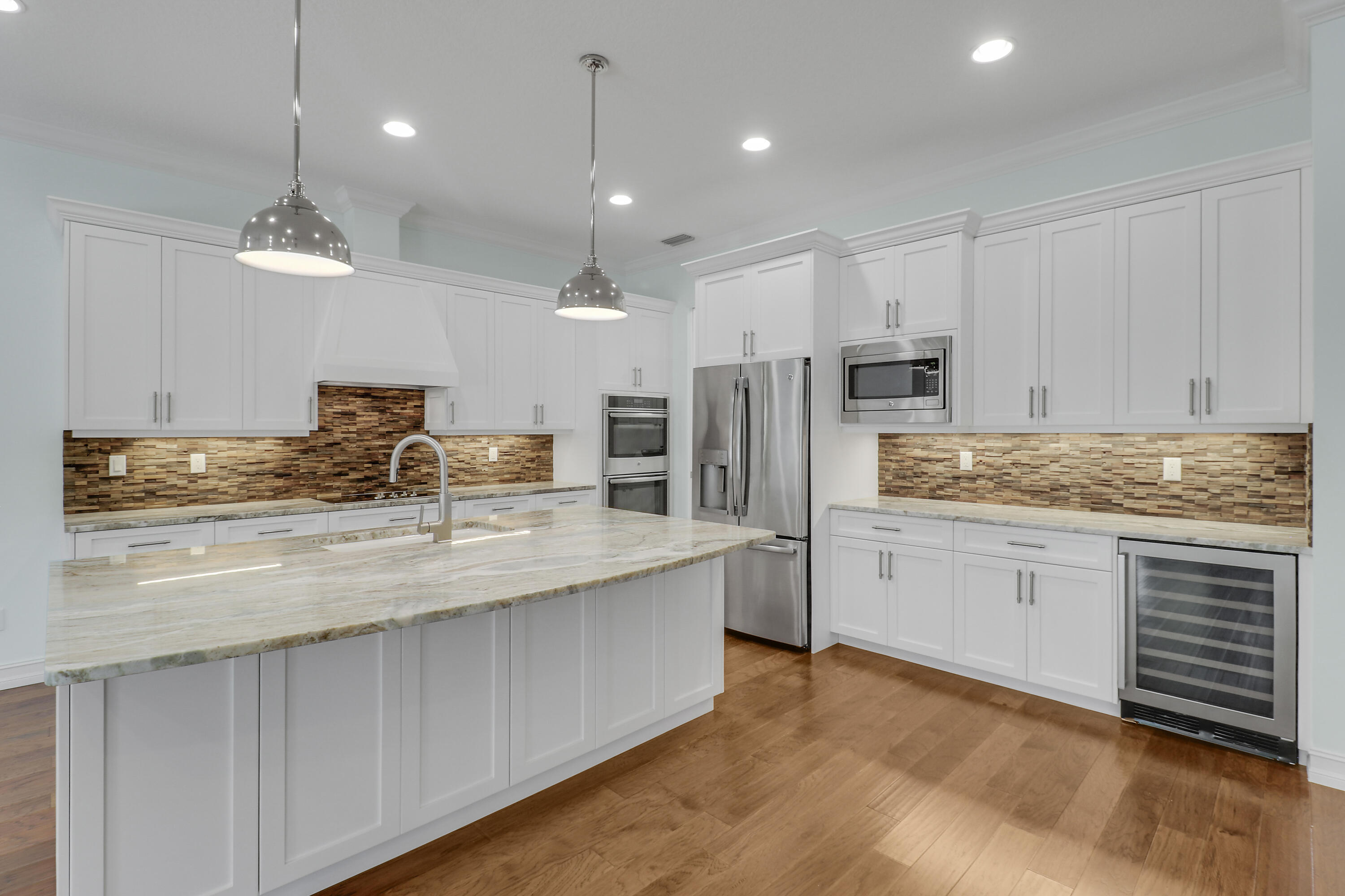 8415 Southeast Governors Way Hobe Sound, FL 33455 - Photo 8 of 105 a kitchen with stainless steel appliances granite countertop a sink refrigerator stove and white cabinets with wooden floor