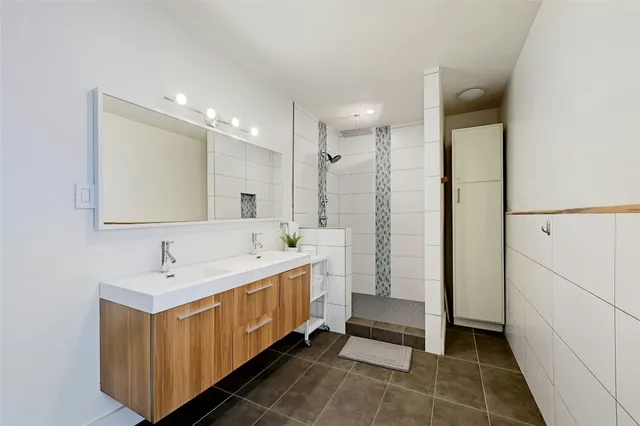 a bathroom with a double vanity sink a mirror and a shower