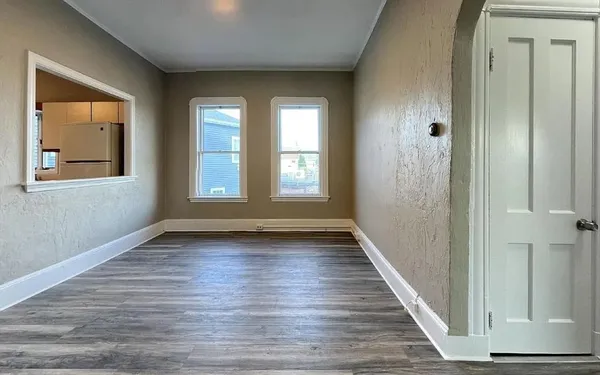 a view of an empty room with wooden floor and a window