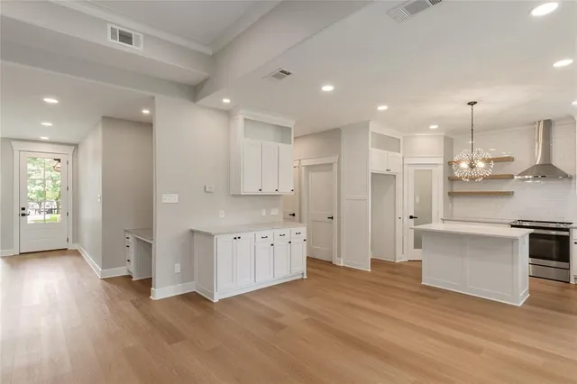 a view of a white house with a large window and a yard with plants and large trees