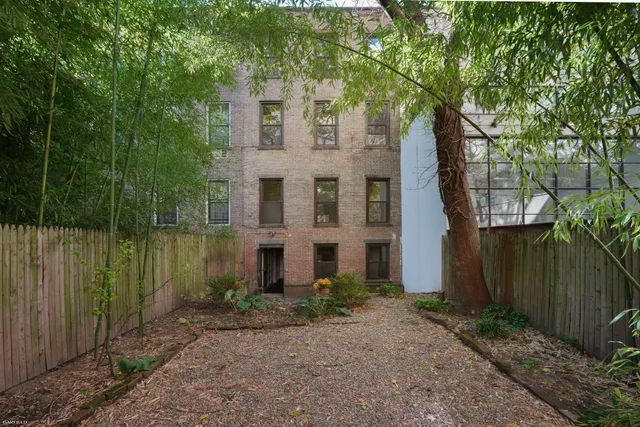 a view of a brick house next to a yard with large trees