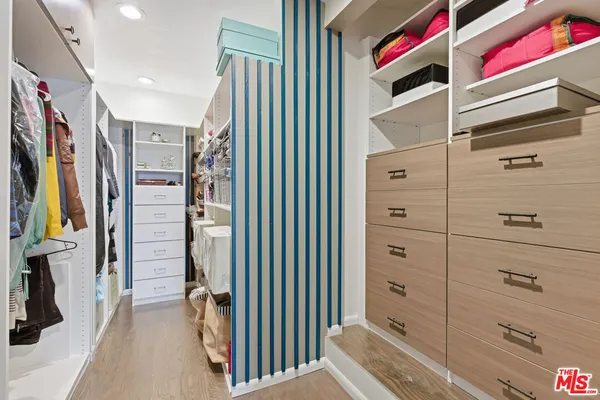 a view of walk in closet with clothes and shoes