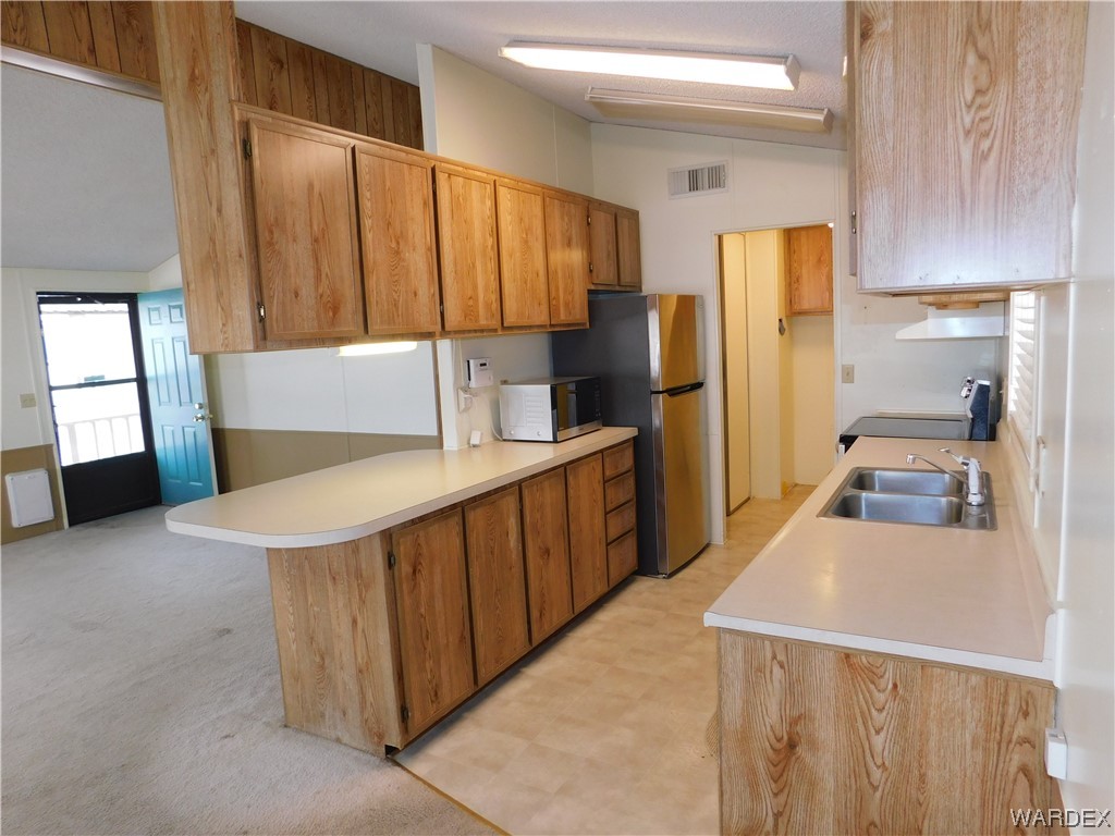 3003 Hualapai Mountain Road, Unit 55 Kingman, AZ 86401 - Photo 27 of 38 a kitchen with stainless steel appliances a refrigerator a sink a stove and cabinets