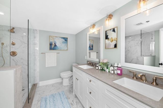 a bathroom with a double vanity sink toilet and shower