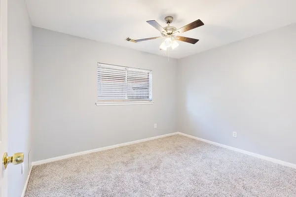 an empty room with a window and a fan
