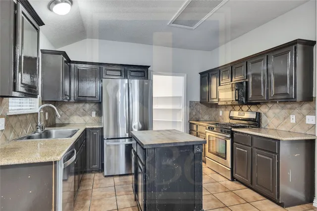 a kitchen with stainless steel appliances granite countertop a sink stove microwave and refrigerator