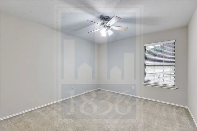 an empty room with windows and chandelier fan