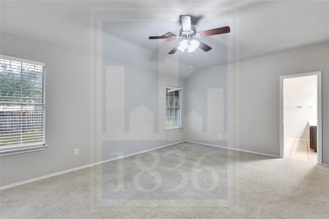 an empty room with chandelier fan and windows
