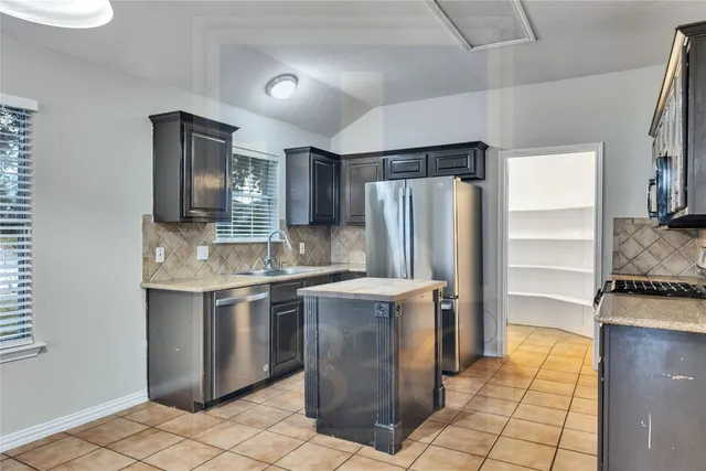 a kitchen with stainless steel appliances granite countertop a refrigerator a stove and a sink