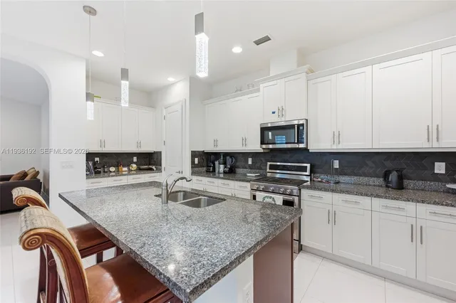 a kitchen with stainless steel appliances granite countertop a sink a stove and a microwave