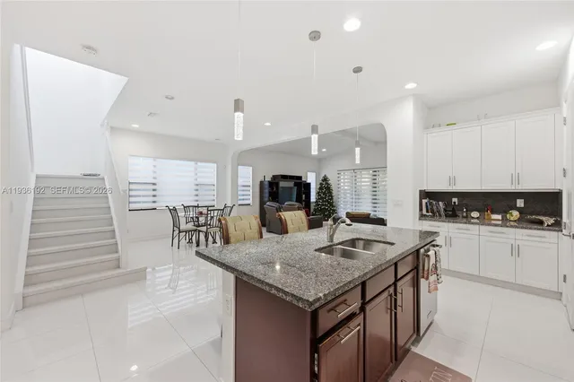 a kitchen with granite countertop kitchen island stainless steel appliances a sink and cabinets