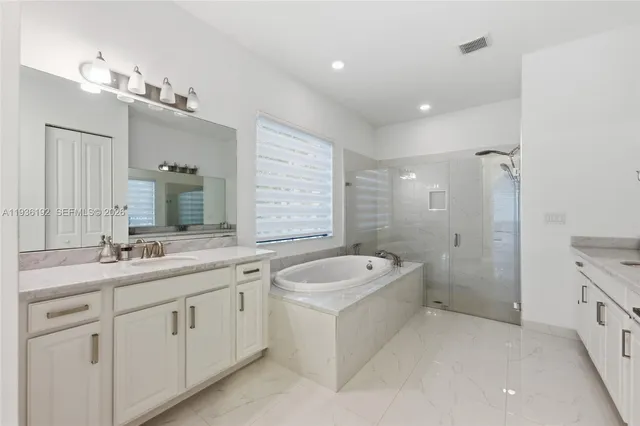 a bathroom with a double vanity sink large mirror and a bathtub