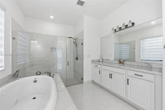 a bathroom with a granite countertop double vanity sink a mirror and a bathtub