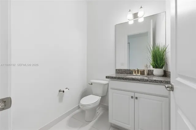 a bathroom with a granite countertop toilet sink and mirror