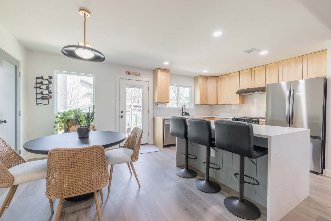 2214 Lear Lane Austin, TX 78745 - Photo 12 of 40 a kitchen with stainless steel appliances granite countertop a refrigerator a stove a sink dishwasher a dining table and chairs with wooden floor