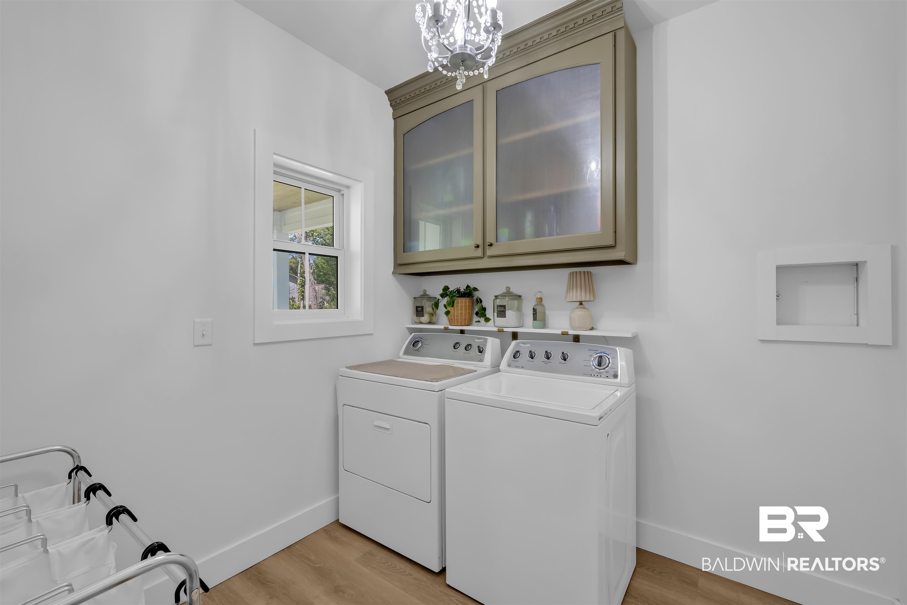 19058 James Road Gulf Shores, AL 36542 - Photo 22 of 49 Laundry area featuring light wood-style flooring, cabinet space, hanging lights, and washer and clothes dryer