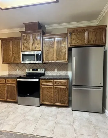 a kitchen with granite countertop a refrigerator and a stove top oven