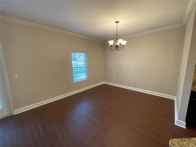 an empty room with wooden floor chandelier and window