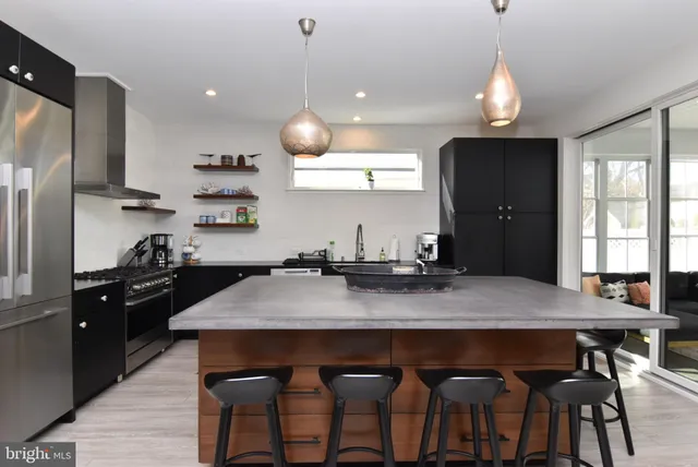 a kitchen with stainless steel appliances granite countertop a dining table chairs refrigerator and microwave