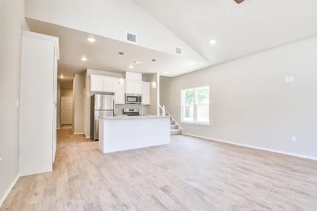 a view of kitchen with kitchen island wooden floor center island and stainless steel appliances